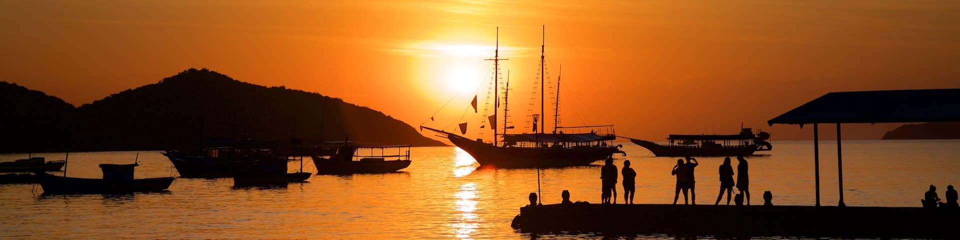 BĂșzios showing a bay or harbor and a sunset as well as a small group of people