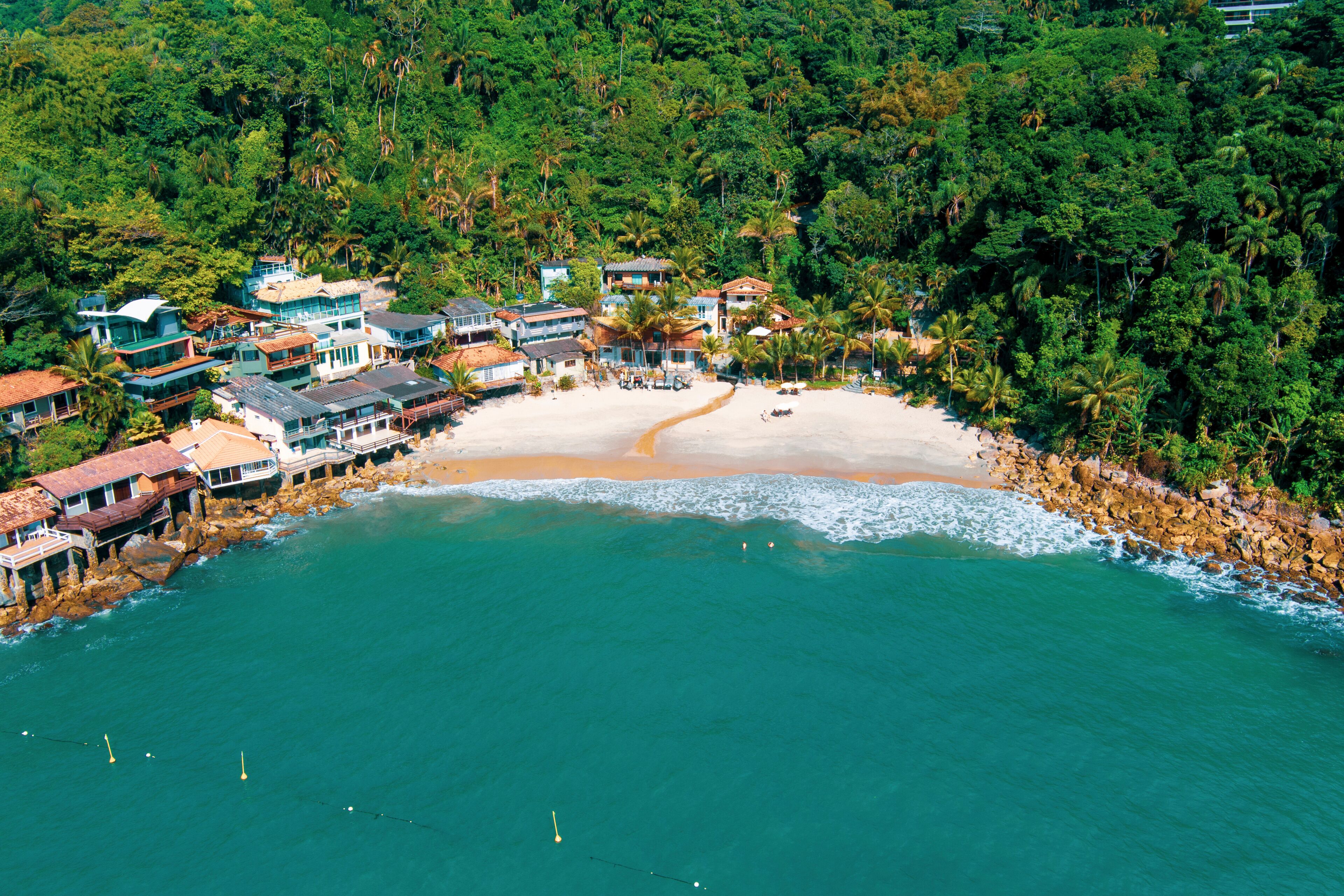 Guaruja. Aerial view of sunny tropical beach with turquoise waves crashing on white sand. Praia do Sorocotuba (Sorocotuba’s Beach), Guarujá, Brazil. 