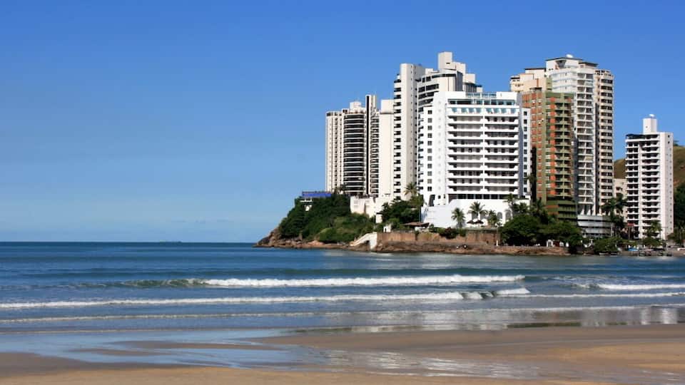 A coastal cityscape with high-rise buildings and a beach.
