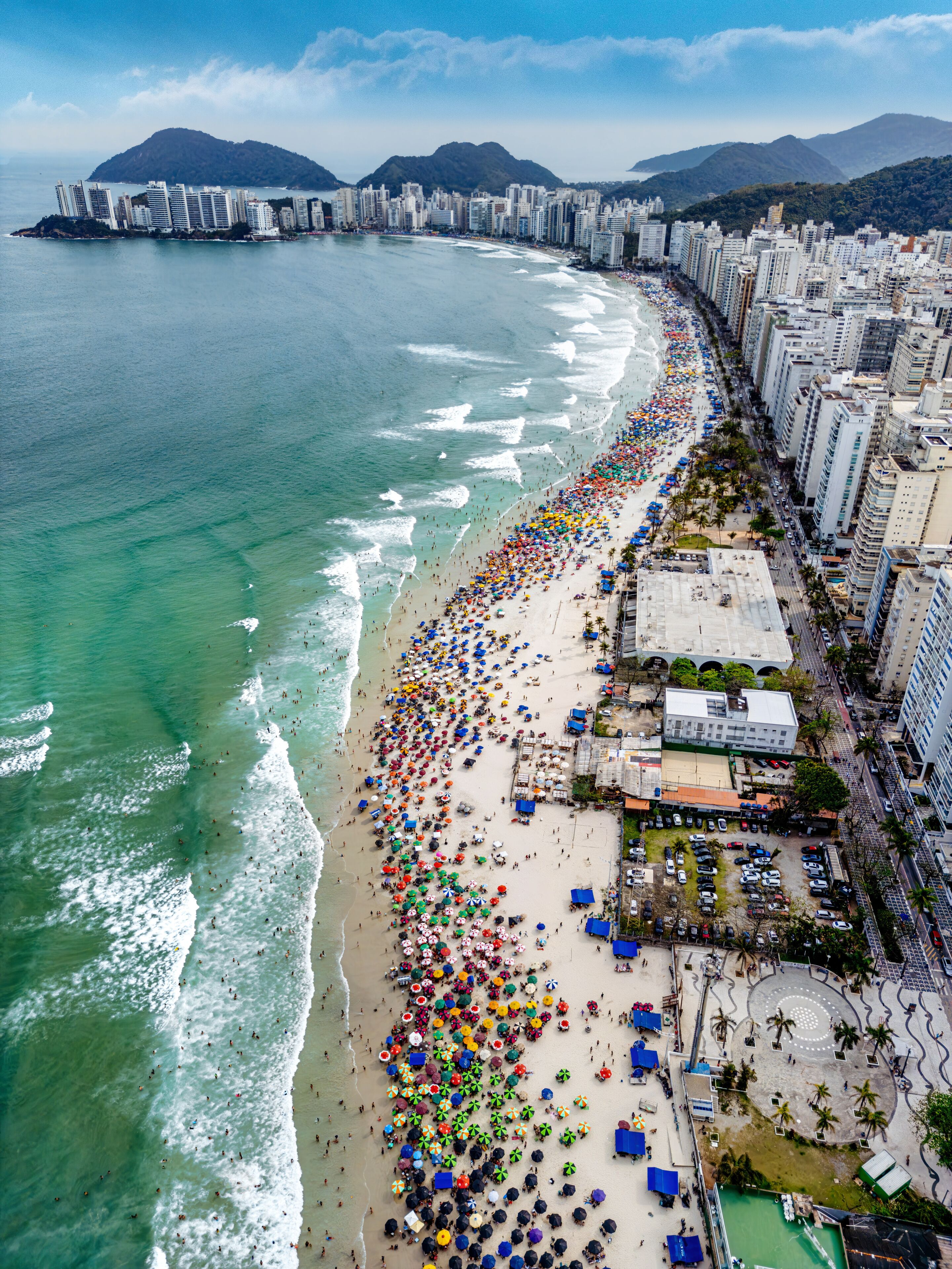 Vista aérea de dia ensolarado com muitos turistas na Praia de Pitangueiras no litoral paulista, Guarujá. 