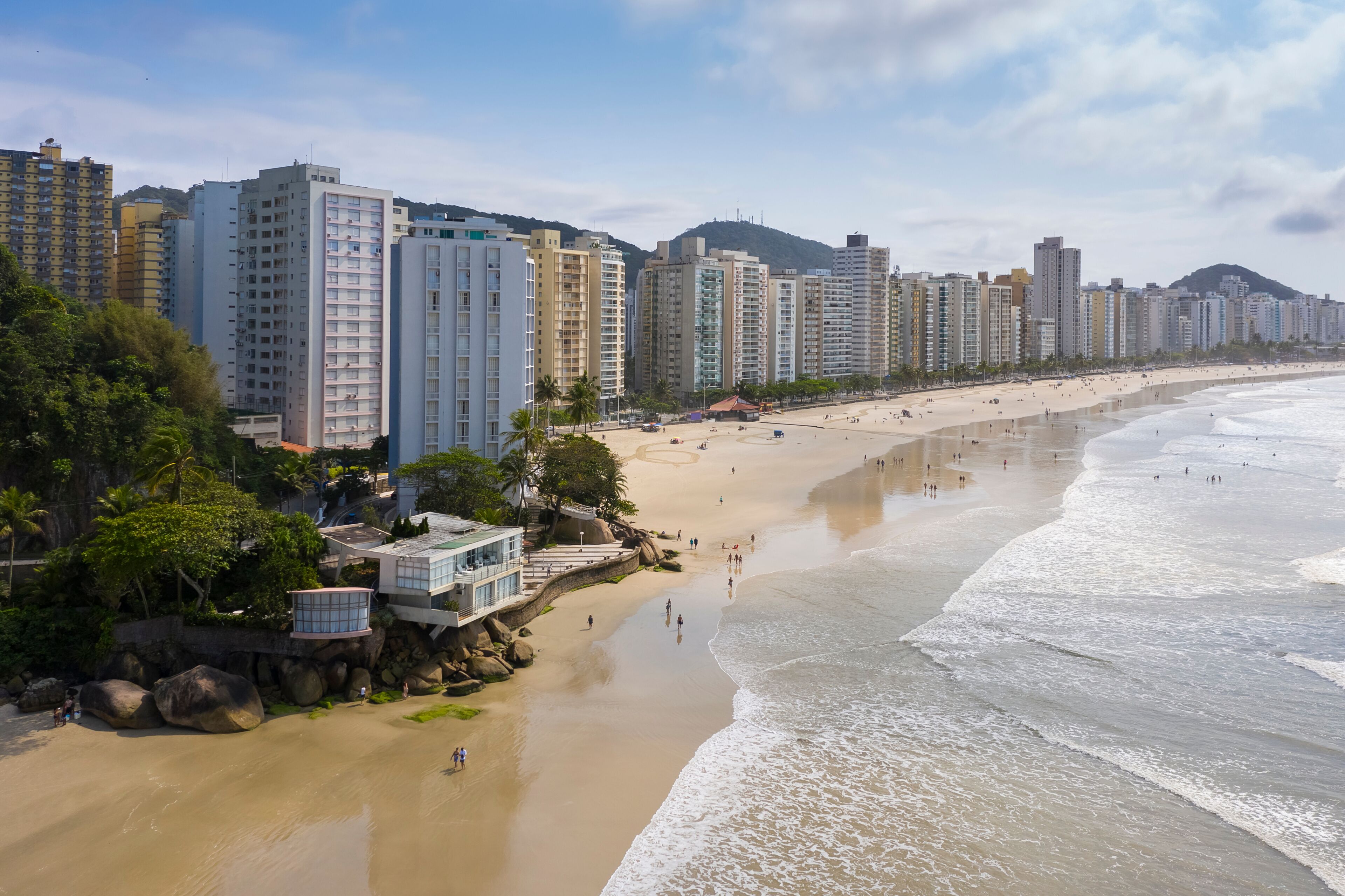 A coastal cityscape with high-rise buildings, a sandy beach, and a mountain in the background.