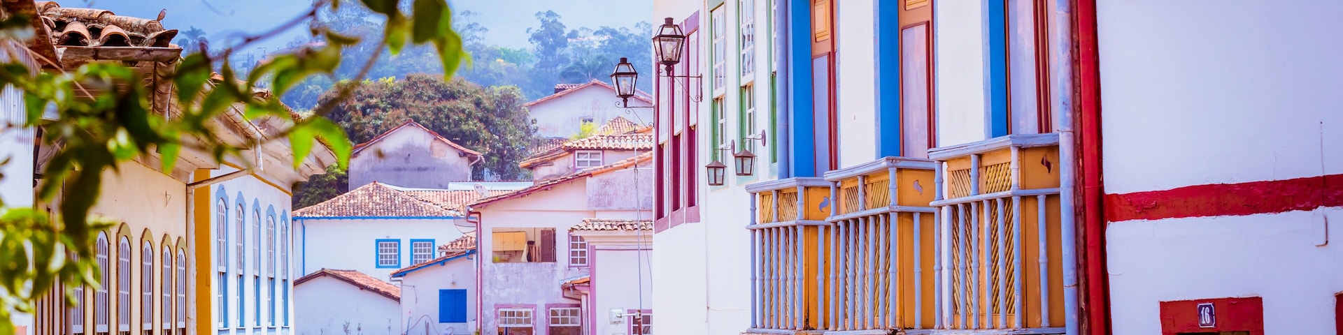 Uma rua colorida com edifícios, um lampião e uma montanha ao fundo.