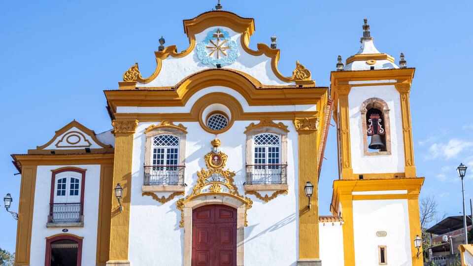 A church with a red door, yellow and white walls, and a bell tower.