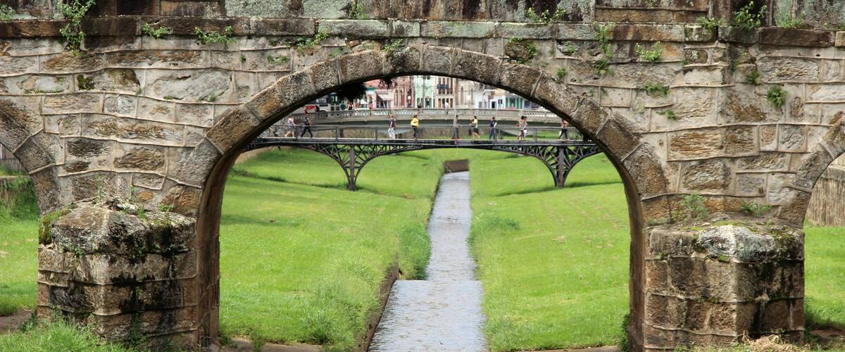 An old stone bridge with a grassy pathway underneath.