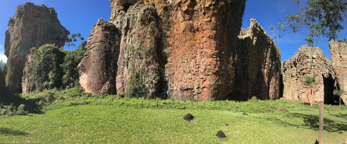 A large rock formation with a grassy foreground and trees.