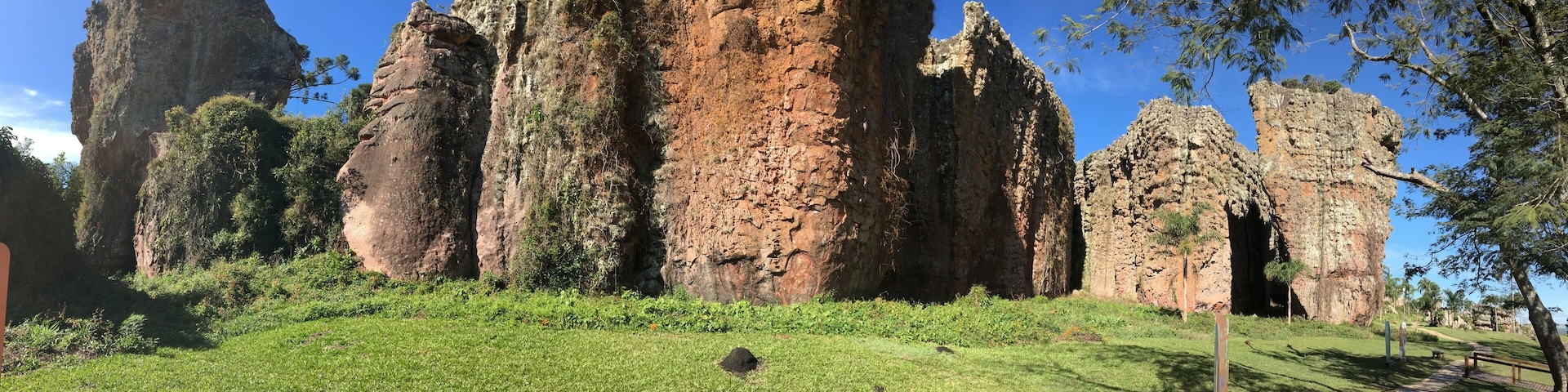 A large rock formation with a grassy foreground and trees.