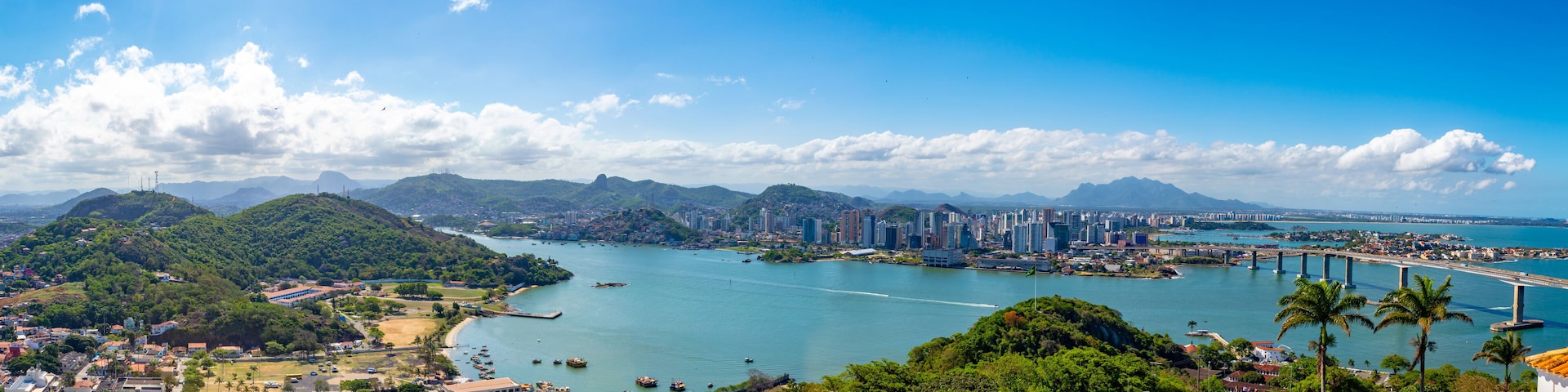 Una ciudad costera con río, puente y colinas circundantes.