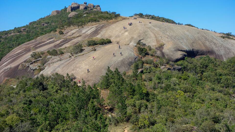 A large hill with a rocky summit and a dirt path leading up.