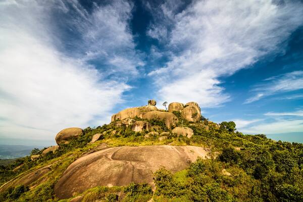 Uma colina com grandes pedras e vegetação verde densa.