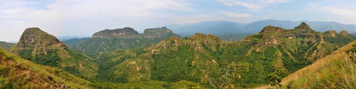 A mountainous landscape with green hills and rocky outcrops.