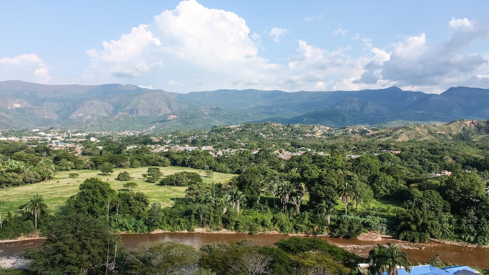 A river, lush greenery, and distant mountains.