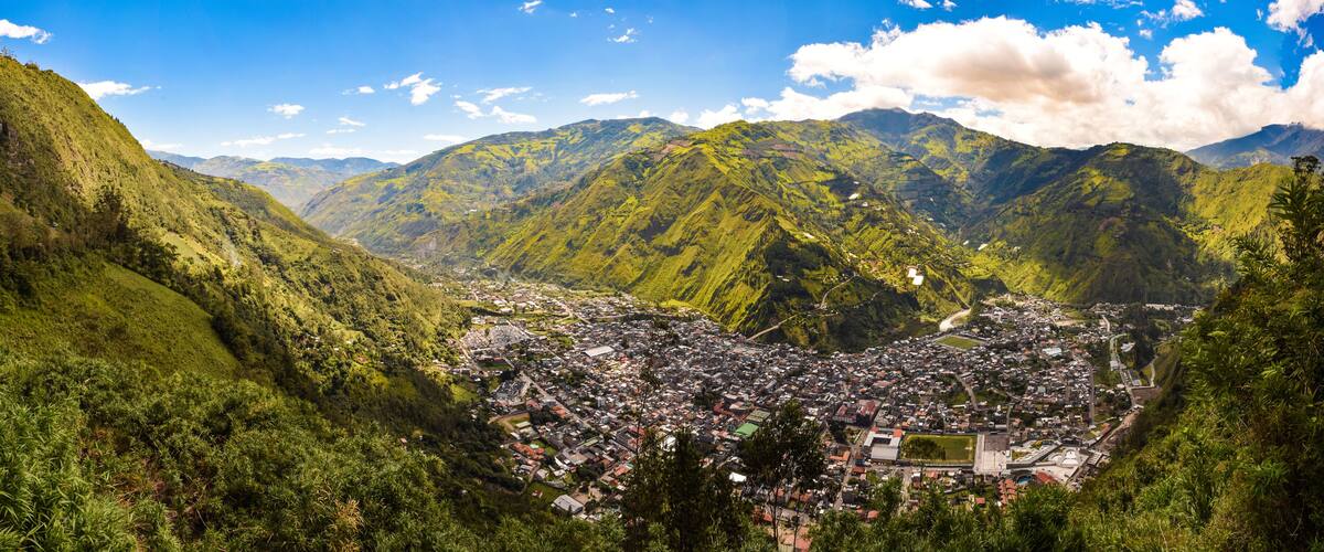 A valley with a town surrounded by lush green mountains.