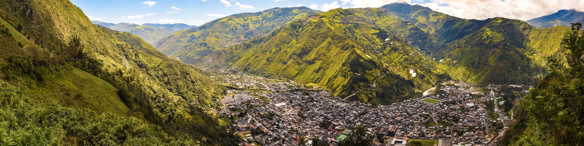 A valley with a town surrounded by lush green mountains.