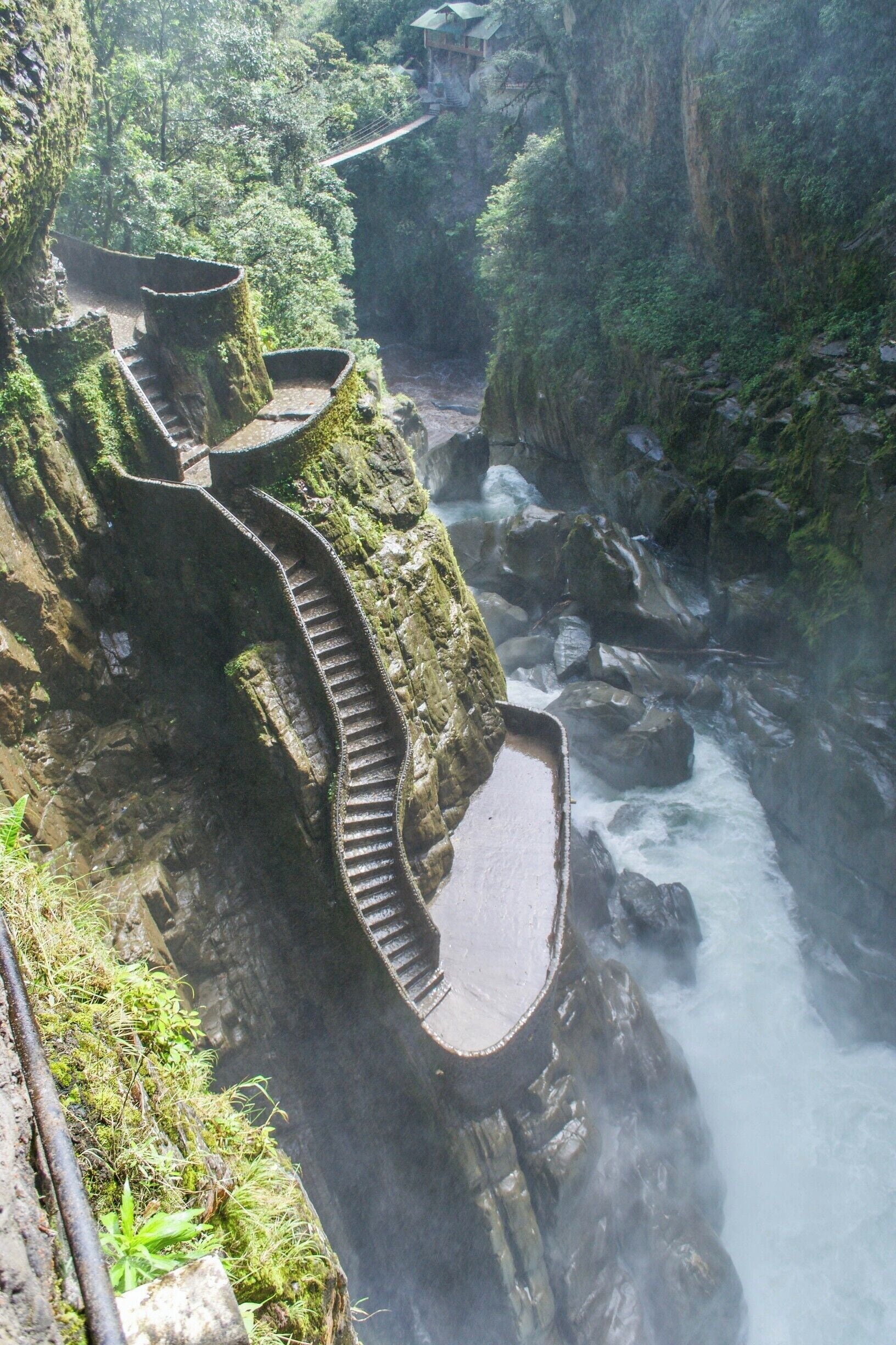 Uma escadaria de pedra serpenteia por um penhasco íngreme, descendo até um rio lá embaixo.