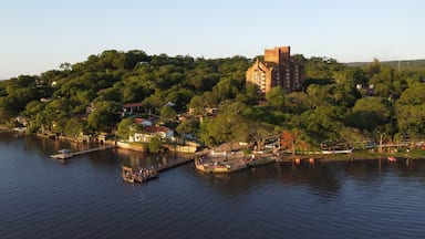 Un pueblo a orillas del río, con un edificio histórico destacado, un muelle y abundante vegetación.
