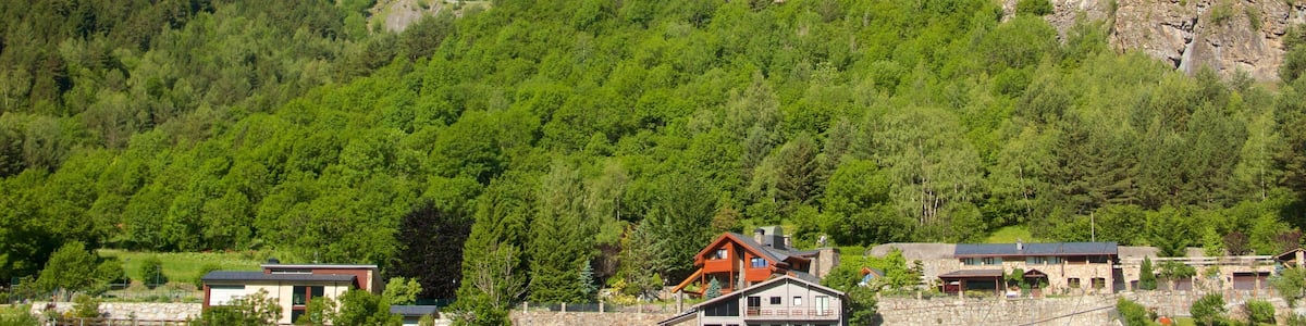 A mountainous landscape with a prominent peak, lush green forests, and a cluster of buildings at the base.