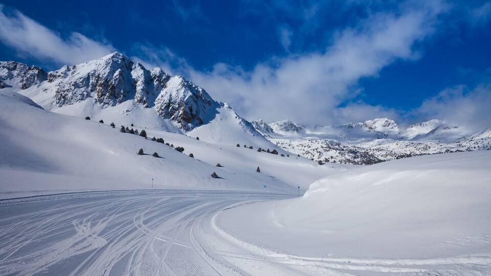A snow-covered mountain landscape with a ski trail.