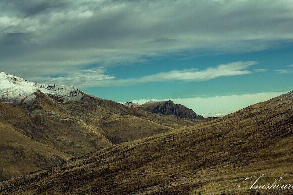 A mountainous landscape with snow-capped peaks and a clear sky.