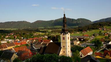 A town with a prominent church tower, surrounded by houses and rolling hills.