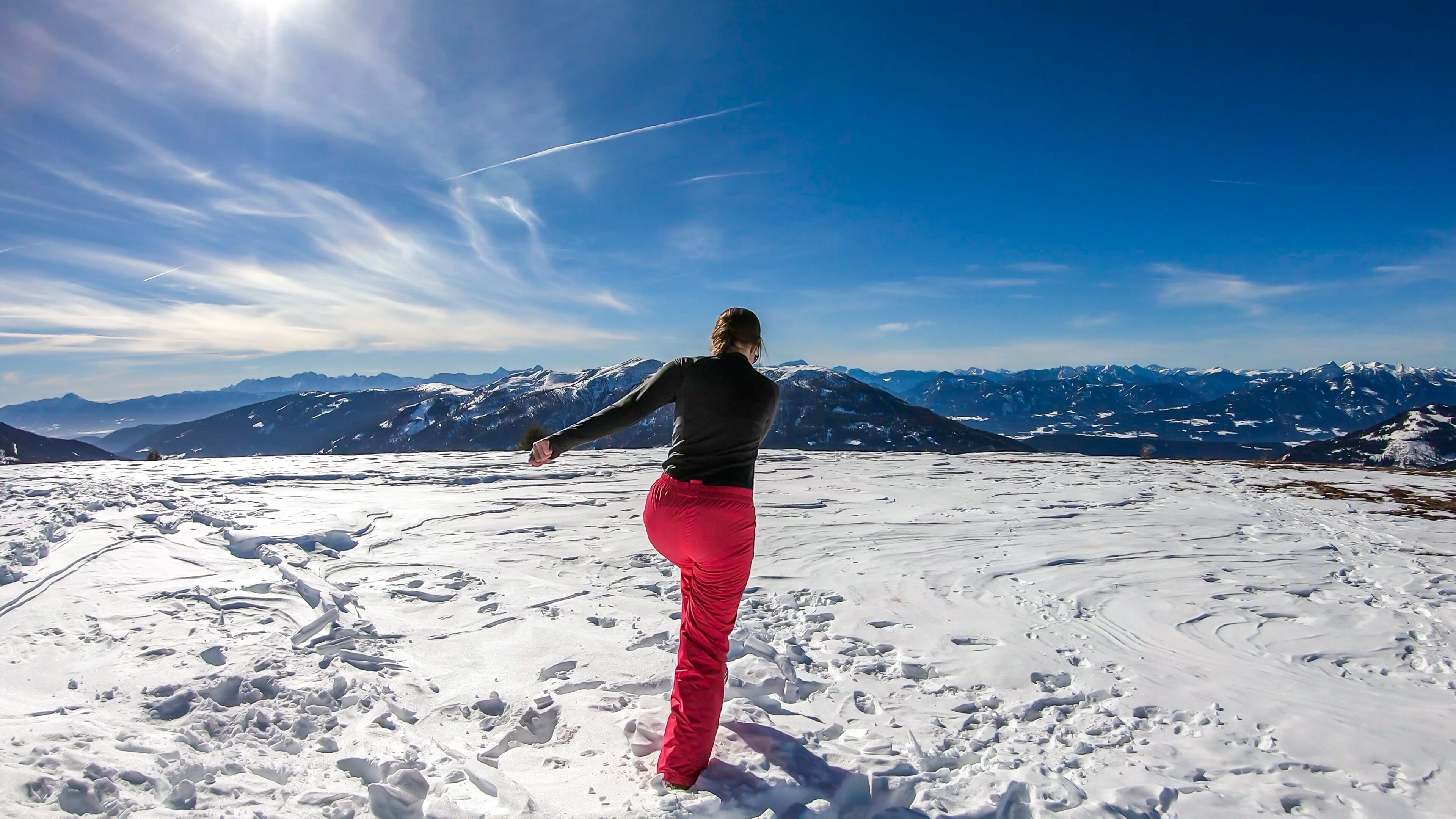 Girl with a snowboarding outfit running on a powder snow, off the trail in Bad Kleinkirchheim, Austria. There are few traits on the snow. Girl is enjoying beautiful weather and view. Freedom and fun