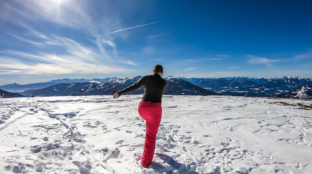 Girl with a snowboarding outfit running on a powder snow, off the trail in Bad Kleinkirchheim, Austria. There are few traits on the snow. Girl is enjoying beautiful weather and view. Freedom and fun