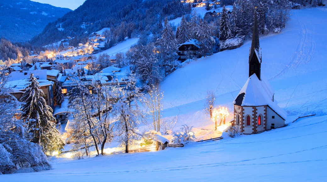A snow-covered village with a church, houses, and a mountain backdrop.