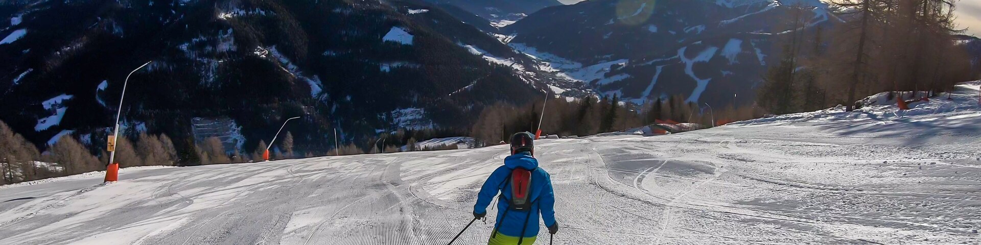 Un esquiador en una pendiente nevada con montañas al fondo.