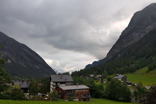 Ein dorfartige Siedlung in den Bergen, mit Häusern, die zwischen üppigem Grün und steilen Klippen liegen.