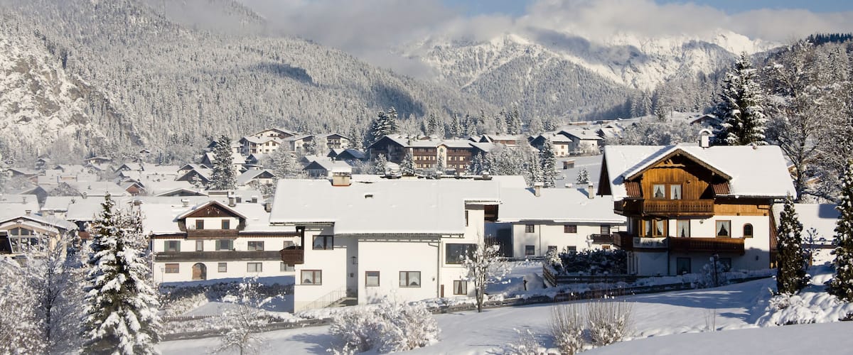 A snow-covered mountain village with wooden houses and a clear blue sky.
