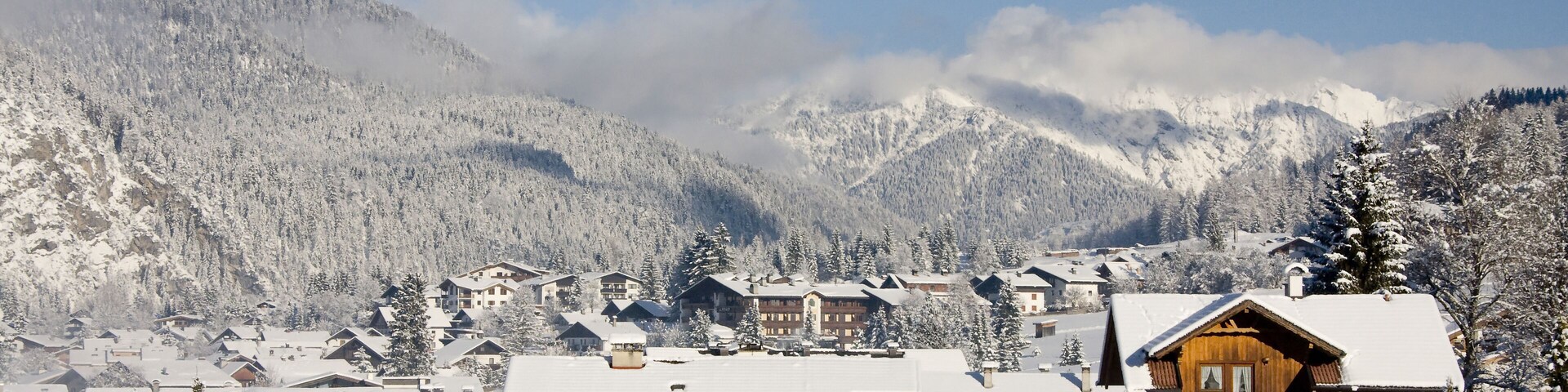 A snow-covered mountain village with wooden houses and a clear blue sky.