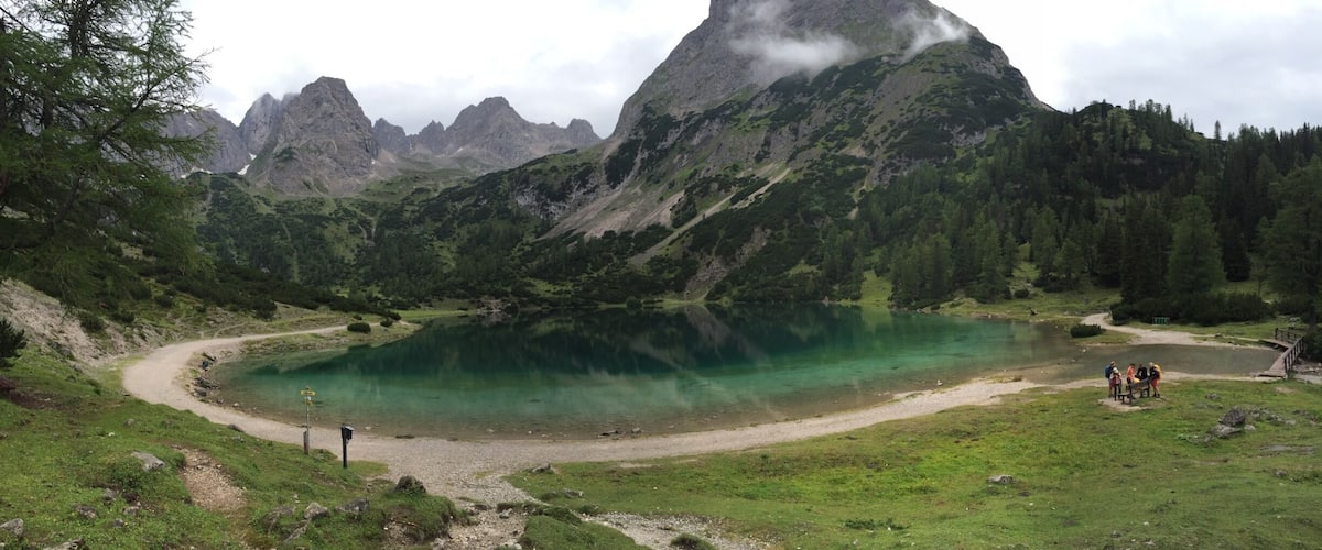 A mountain lake surrounded by forested hills and a clear sky.