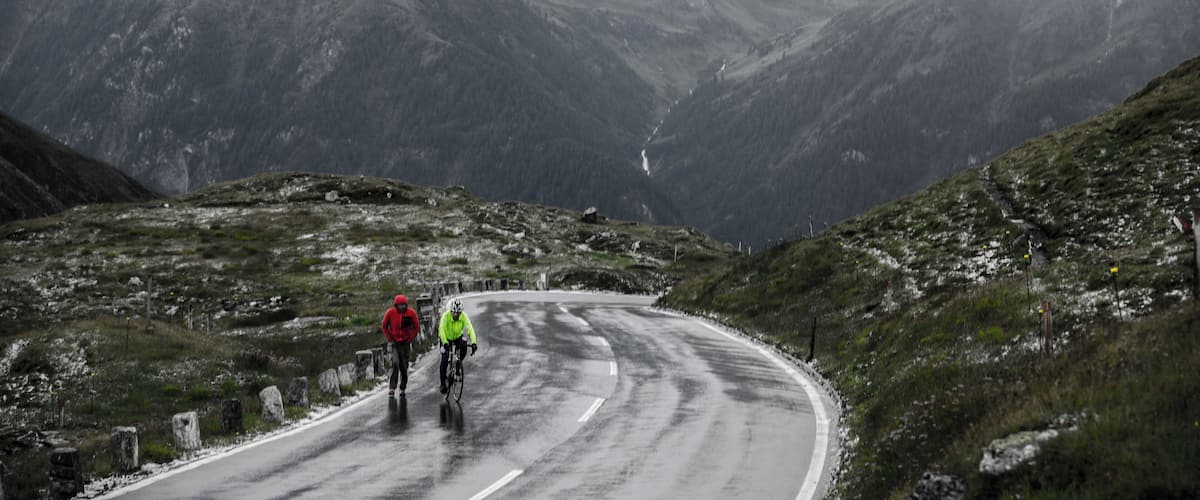 A winding road through a mountainous landscape with two cyclists.