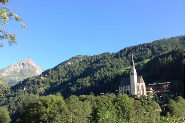 A church surrounded by lush green hills and a clear blue sky.