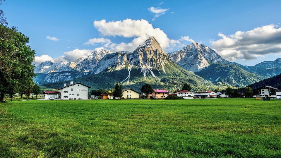 A village with houses in a valley, surrounded by mountains.