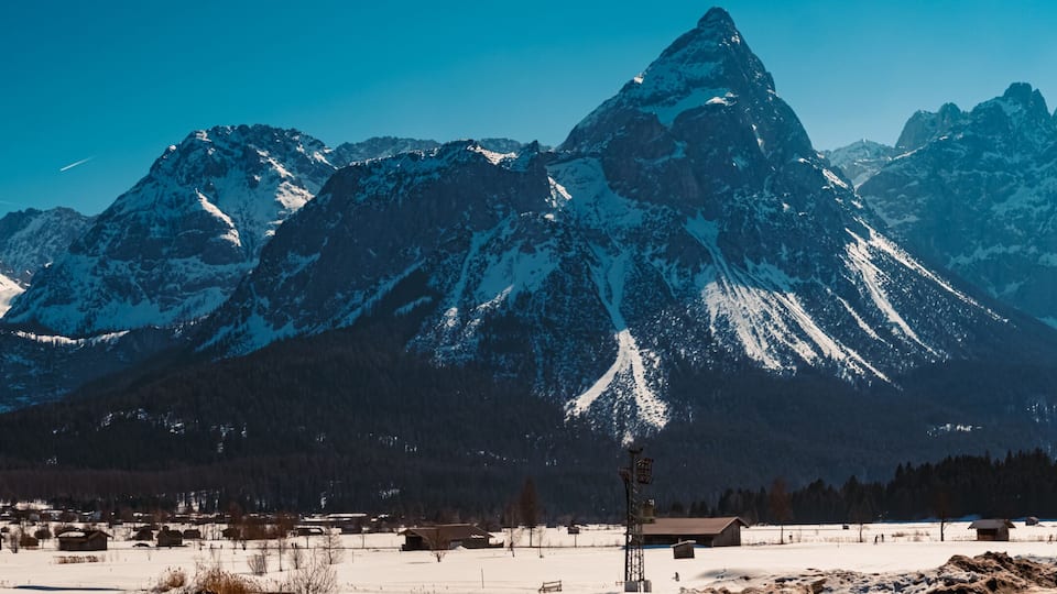 A snow-covered mountain range with a small village in the foreground.
