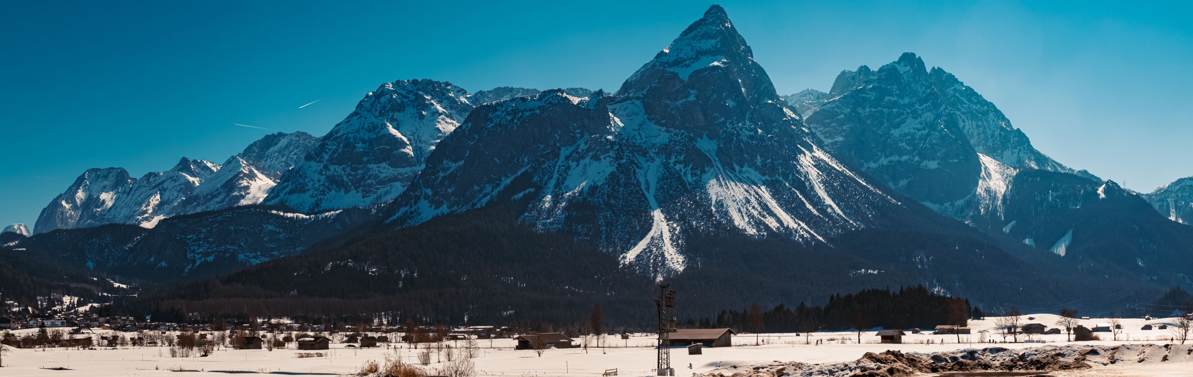 A snow-covered mountain range with a small village in the foreground.