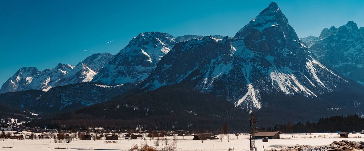 A snow-covered mountain range with a small village in the foreground.