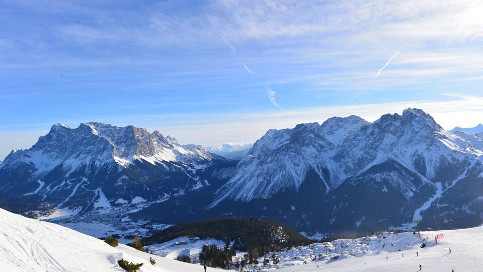 A snow-covered mountain range with ski slopes and a clear blue sky.