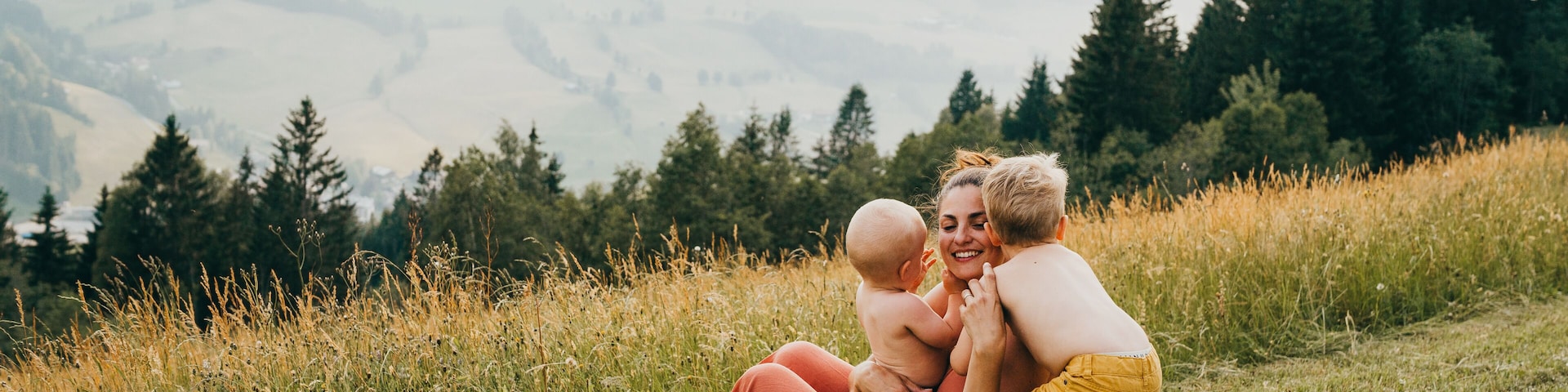 Una familia en un campo con montañas al fondo.