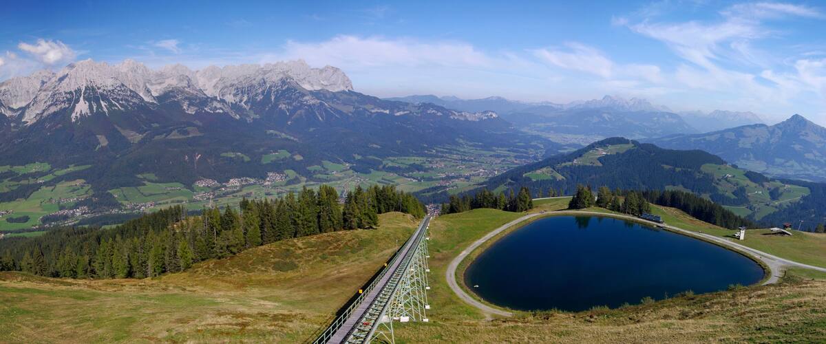 A mountain landscape with a lake, a railway track, and a village.