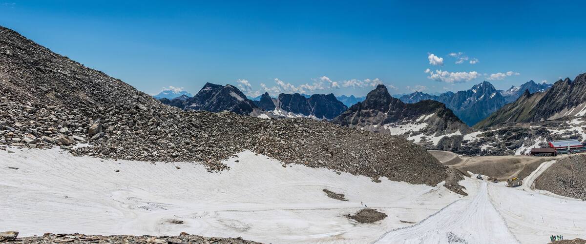 A snowy mountain landscape with rocky terrain and a red building in the distance.