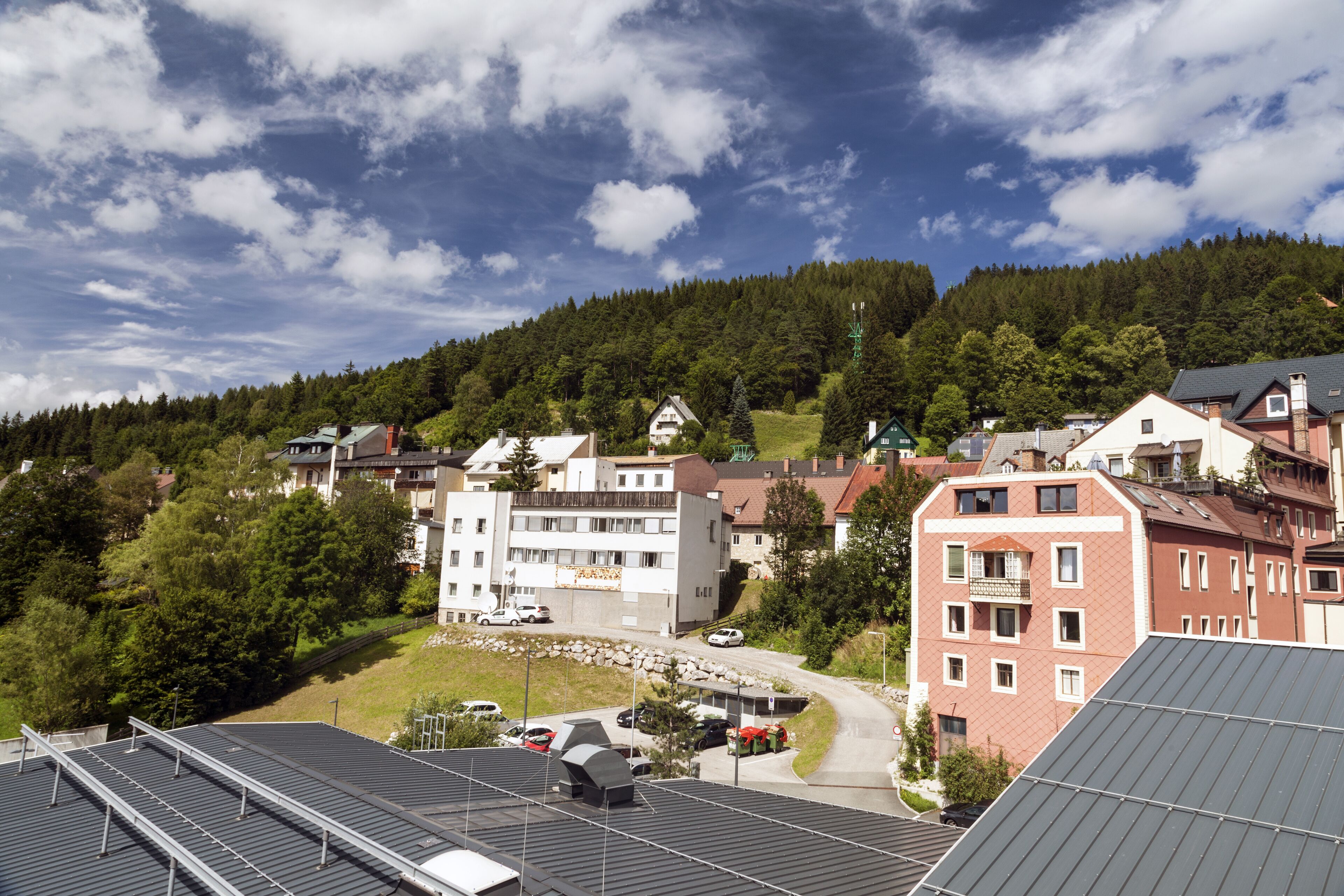 A town with buildings, a road, and a forested hill in the background.