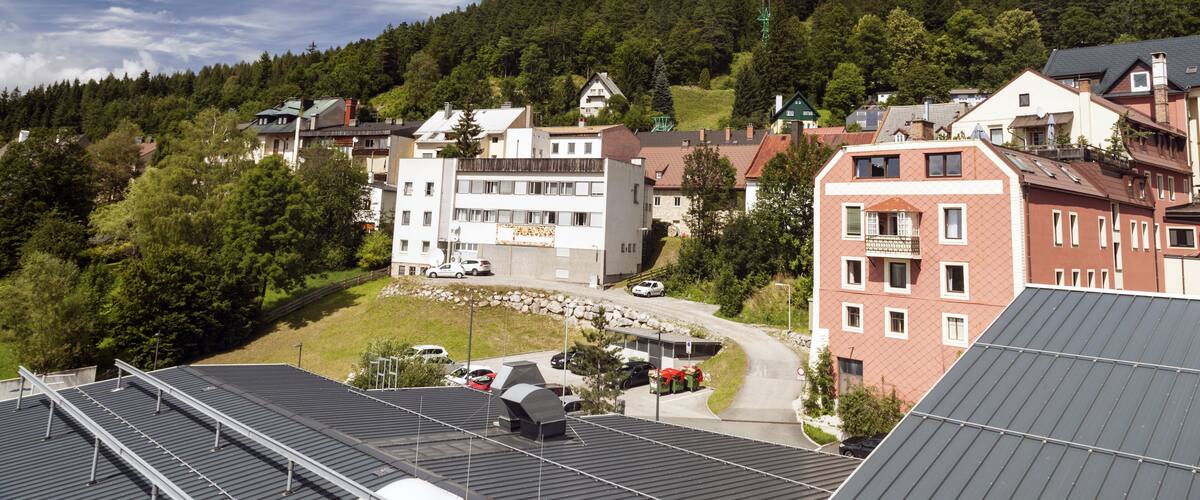 A town with buildings, a road, and a forested hill in the background.