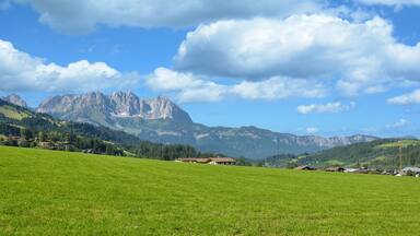 A green field, a church, and mountains in the background.