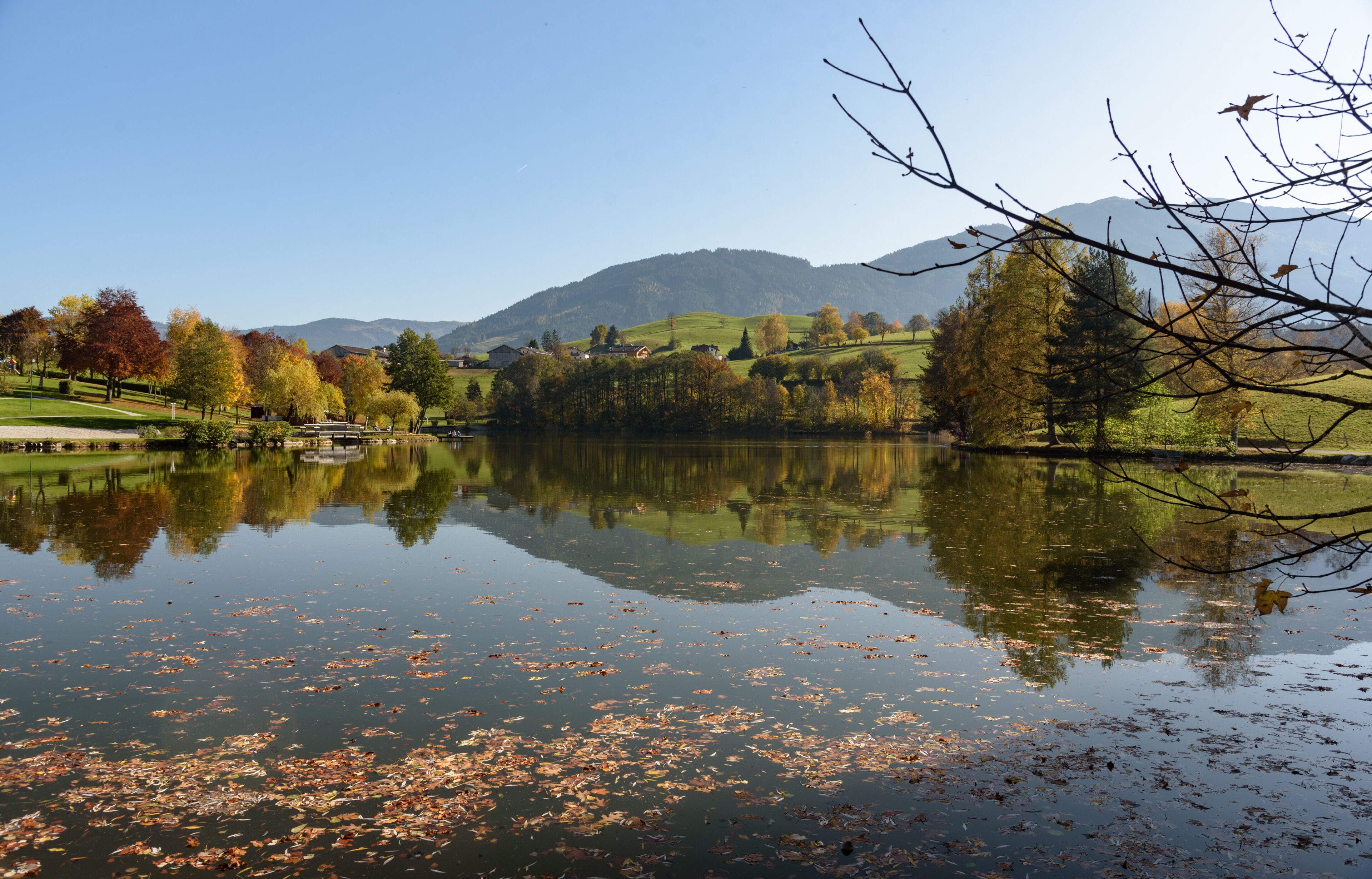 View of Lake Ritzensee on a sunny autumn day in Saalfelden with still reflecting water mountain with clear blue sky. Saalfelden, Pinzgau, Salzburg Land, Austria.