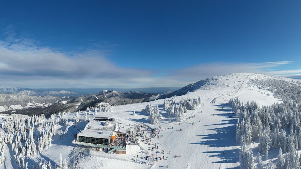 A snow-covered mountain with a ski resort, including a building and ski slopes.