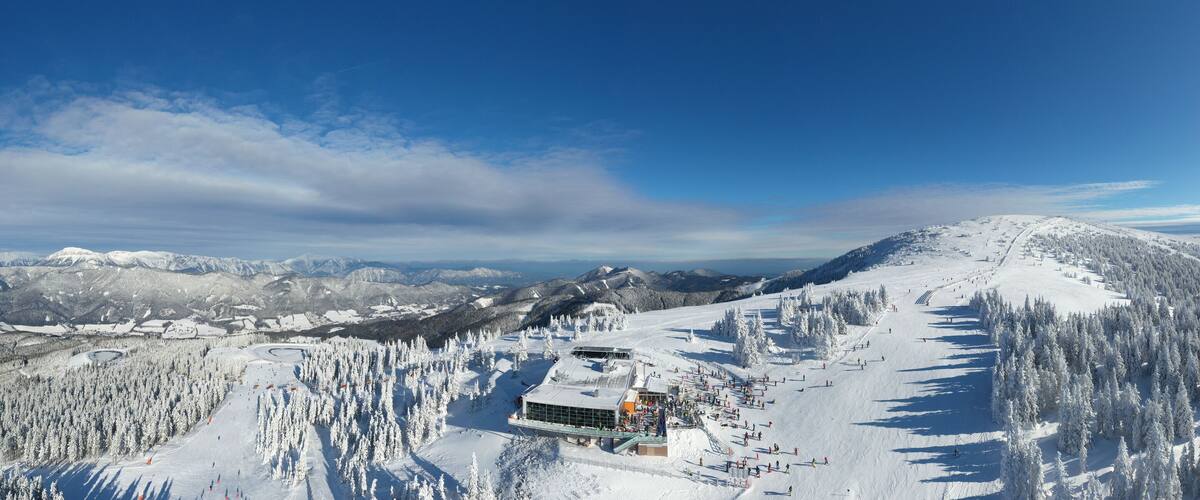 A snow-covered mountain with a ski resort, including a building and ski slopes.