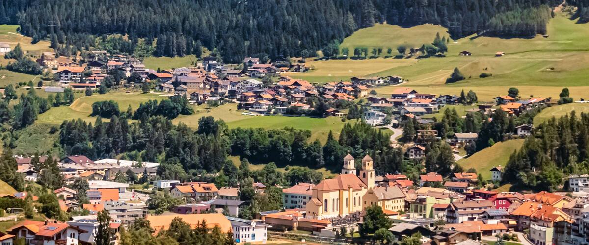 A picturesque village nestled in a valley with a prominent church and rolling hills in the background.