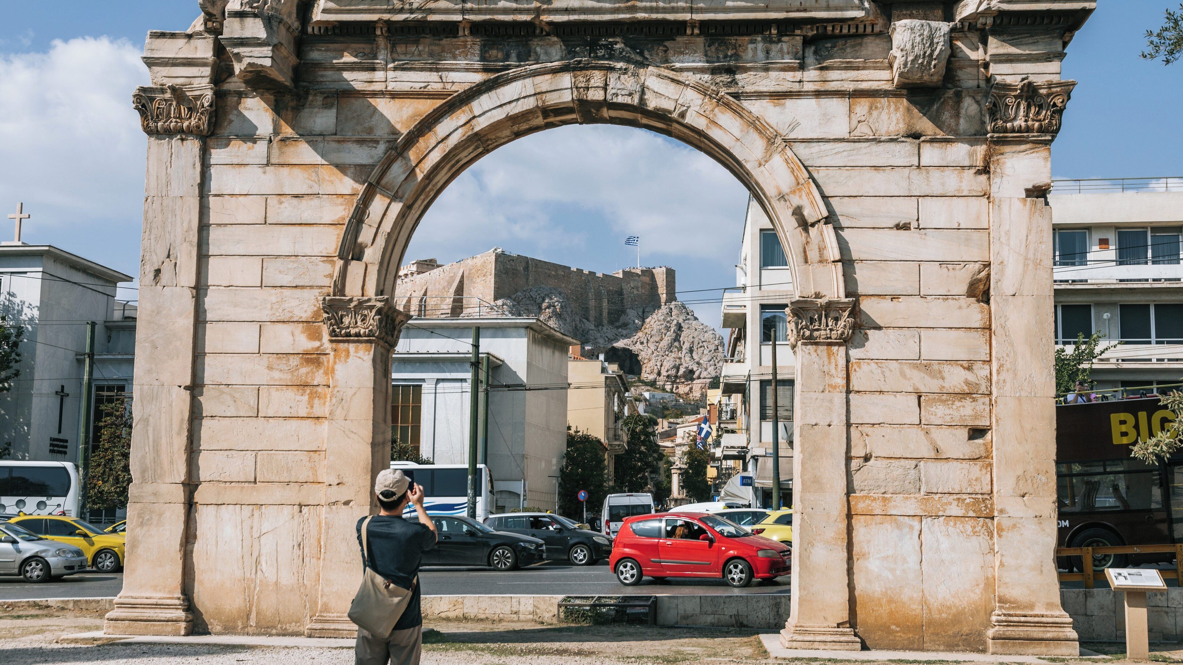 Capturing the majestic Temple of Olympian Zeus through the Arch of Hadrian in Athens, highlighting the vibrant city life and historical architecture