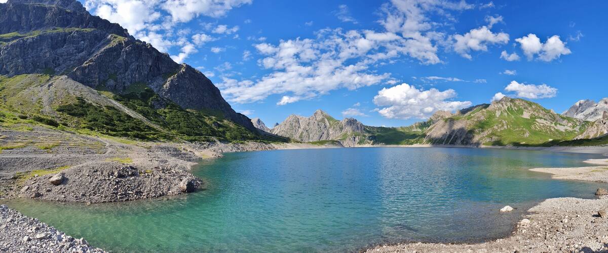 A mountain lake surrounded by rocky terrain and green hills.